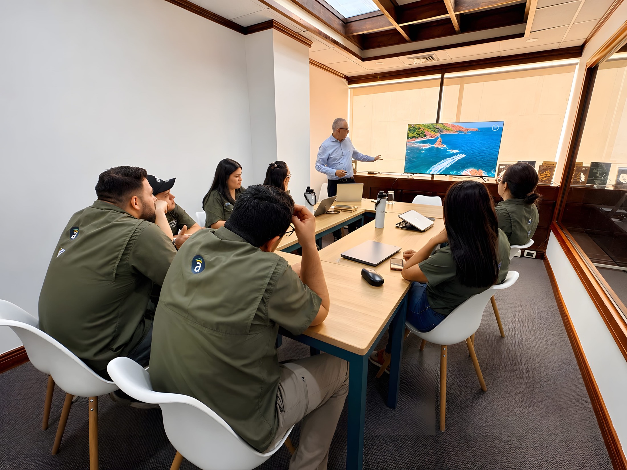 El equipo de Asuaire en una sesión de trabajo en su oficina de Costa Rica, con una vista aérea de la costa en pantalla.
